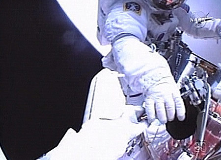 In this May 14, 2009 image taken from NASA video, astronaut John Grunsfeld (top) gives a tool to colleague Drew Feustel during the first space walk to repair the Hubble space telescope